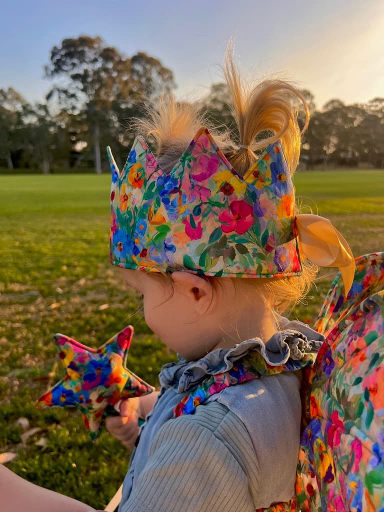 Young child wearing a painted floral crown with a matching star wand and wings