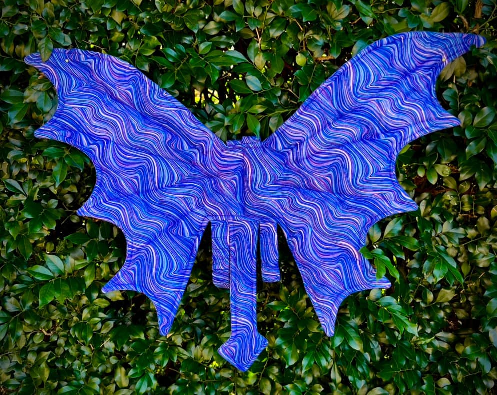 Amethyst Current handmade dragon wings displayed against deep green leaves