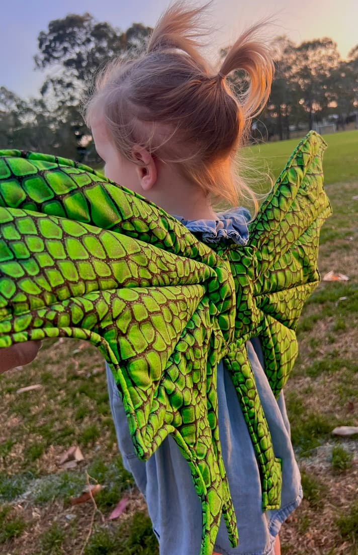 Close view of emerald dragon wings worn by a young child