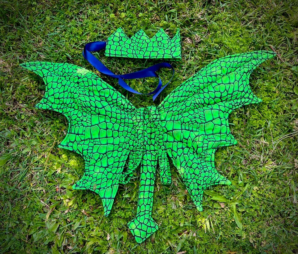 Emerald dragon wings and a matching crown arranged on grass